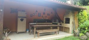 an outdoor kitchen with a picnic table and a refrigerator at Chalé Schueler in Nova Friburgo