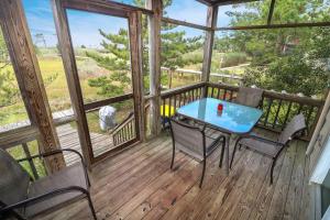 a porch with a table and chairs on a deck at Marsh Point - Screened Porch & Shared Dock! in Black Point Landing