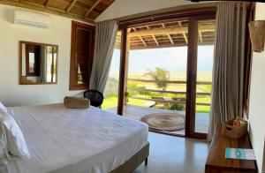 ein Schlafzimmer mit Bett und Blick auf das Meer in der Unterkunft Casa do vento - Ilha do Guajiru in Itarema
