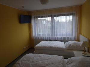two beds in a room with a window at Hotel-Pension Schlossgarten in Trippstadt