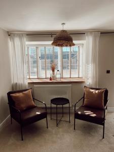 ein Wohnzimmer mit 2 Stühlen, einem Tisch und einem Fenster in der Unterkunft Gardener's Cottage in Chepstow