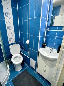 een blauw betegelde badkamer met een toilet en een wastafel bij The Box in Iaşi +2 foto's