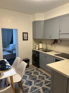 a kitchen with white cabinets and a table and chairs at D&D Apartments in Tirana