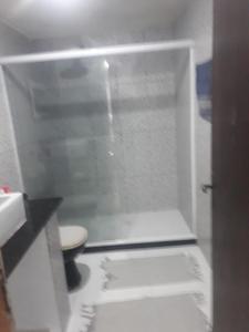 a white bathroom with a shower with a toilet at Pousada por do sol in Niterói