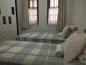 2 aparte bedden in een slaapkamer met ramen bij Quarto Due na Sakura House in Indaiatuba