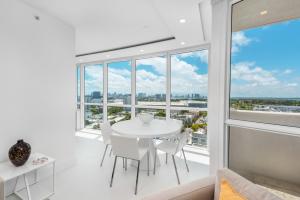 a white dining room with a table and chairs and a large window at 4B Super Premium Private Condo at the Setai in Miami Beach