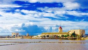 a building with a windmill in the middle of a body of water at The house of the islands Sea view in Marausa