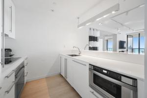 Una cocina blanca con fregadero y espejo. en Ocean View Residence at South Beach -1614, en Miami Beach
