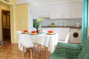 una cocina con mesa y sillas y una cocina con armarios blancos. en Apartamento Barramundi, en Peñíscola