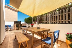 a patio with a wooden table and chairs and an umbrella at Casa Marino Formentera in Sant Francesc Xavier