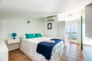 a white bedroom with a bed and a balcony at Casa Marino Formentera in Sant Francesc Xavier