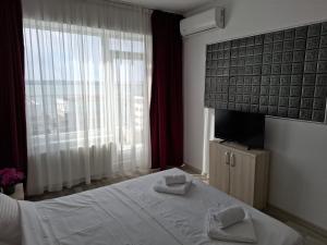 a bedroom with a white bed and a television at Apartament cu terasa si vedere, Mamaia Nord, Zona SummerLand in Mamaia