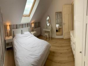 une chambre avec un lit blanc et un miroir dans l'établissement Spacious, 2-level holiday apartment, à Grzybowo