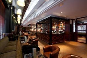 a restaurant with a bar with leather chairs and tables at Hotel 1898 in Barcelona