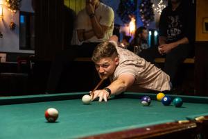 a man laying on a pool table with a cue at Wild Rover La Paz in La Paz