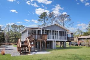 a large house with a large deck and stairs at Our Happy Place - Pet friendly & waterfront! in Deep Hole