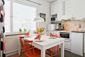 a white kitchen with a white table and chairs at Majoitushuoneisto Tuomipuisto in Naantali