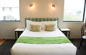 a bedroom with a large white bed with two windows at Bella Vista Motel Mosgiel in Mosgiel +15 photos
