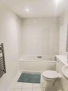 a white bathroom with a toilet and a bath tub at Room with private bathroom, Near Heathrow Airport, Tube Station, Shops, Cinema in shared flat in Hounslow +8 photos