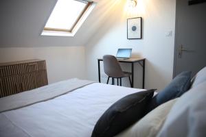 a bedroom with a bed and a desk with a laptop at L'Attique, confort, aéré, centre-ville, Netflix in Laval