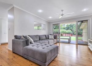 sala de estar con sofá gris y chimenea en Lamington Cottage, en The Range