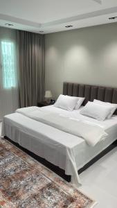 a large white bed in a bedroom with a rug at شقة الصفا in Al ‘Utaybīyah +4 photos