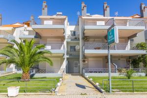 an apartment building with a palm tree in front at Dimitra Boutique Apartments 1 in Keramoti