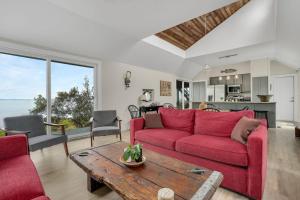 a living room with a red couch and a table at Poole's Cove - Waterfront; Main Street! in Deep Hole