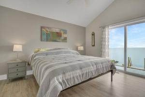 a white bedroom with a bed and a large window at Poole's Cove - Waterfront; Main Street! in Deep Hole