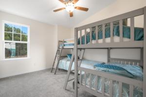 a bedroom with two bunk beds and a ceiling fan at Robert's Retreat - Brand new home w/ gorgeous water views! in Greenbackville