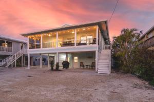 a large white house with a sunset in the background at Lazy Lobster by Sun Palace Vacations in Fort Myers Beach