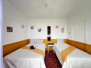 deux lits dans une chambre avec des draps blancs dans l'établissement Casa del viajero Antigua, à Antigua Guatemala