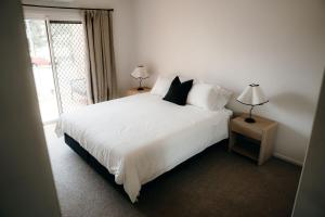 a bedroom with a large white bed with two lamps at Unit 4, Rocky CBD in Rockhampton