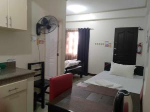 a small room with a bed and a table and a kitchen at V.F. Riton Apartelle in Laoag