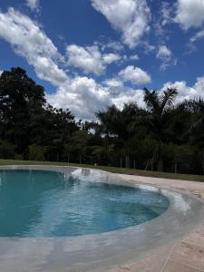 an empty swimming pool with a blue sky and palm trees at Villa Dois Amores in Lindóia