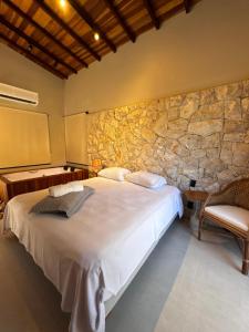a bedroom with a large bed and a stone wall at Villa Dois Amores in Lindóia