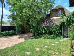 a house with a thatched roof and a yard at Urban Villa 25 in Gaborone