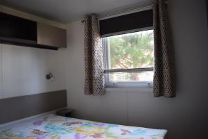 un dormitorio con una cama y una ventana en Mobile home - Bonne Anse La Palmyre - 8 pers, en Les Mathes
