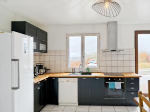 a kitchen with black cabinets and a white refrigerator at Gîte le Bistrot, 3ch, 6pers in Saint-Pantaléon-de-Lapleau