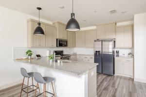 a kitchen with white cabinets and a island with bar stools at Stylish Living in Vibrant Frisco in Frisco