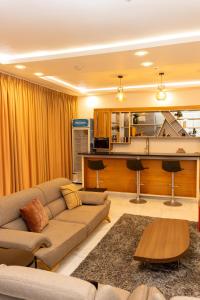 Una sala de estar con un sofá y una cocina. en De Cove, en Ogbojo