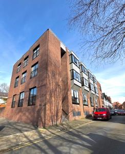 een bakstenen gebouw met een rode auto ervoor geparkeerd bij Chester's - Central Chester Stays - 2 Cuppin Street - 2 Minute Walk From Shops in Chester