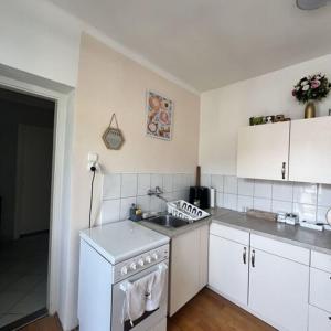Una cocina blanca con fregadero y estufa. en Bem Apartman, en Gyenesdiás 8 fotos más