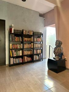 una estantería llena de libros junto a una estatua en Casa Dos Antonios en Zona Viva de Puerto Vallarta, en Puerto Vallarta