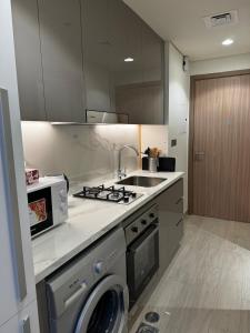 ドバイにあるSunlit serenity Studio Azizi Rivieraの洗濯機と電子レンジ付きのキッチン