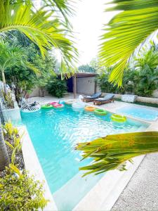 Luxury House Tomanoa - 10pers - 4rooms - Pool - HotJacuzzi - Speed Wifi -waterfall في تولوم: حمام سباحة مع قوارب ملونة في الفناء الخلفي
