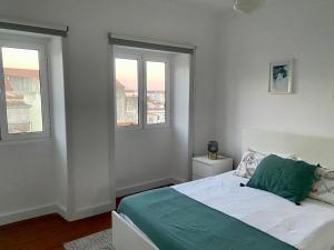 een witte slaapkamer met een bed en twee ramen bij Retiro dos Reis in Horta