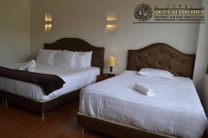 a hotel room with two beds with white sheets at Hotel PUENTE PIEDRA PARK in Villa de Leyva +15 photos