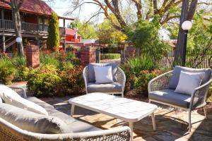 a patio with three chairs and a table and a coffee table at Kaesler Cottages in Nuriootpa