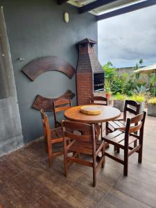a wooden table and chairs with a fireplace on a patio at Casa Aconchegante em Condomínio Country in Conde